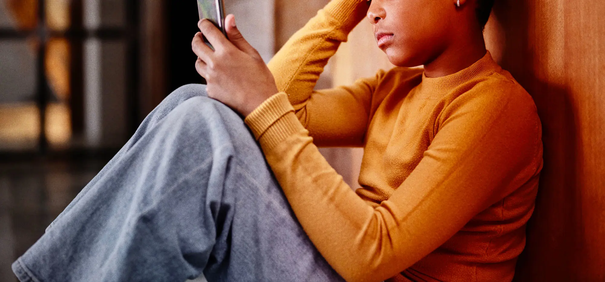 IWF CEO Job Girl in orange jumper looking at phone