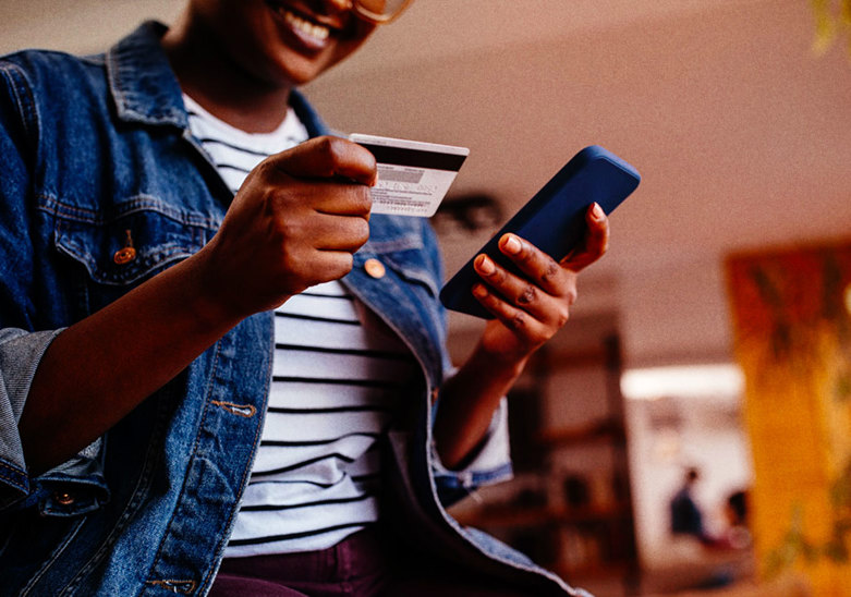 Woman shopping online with credit card and phone in hands