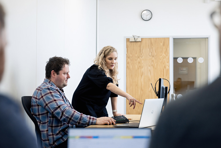 Two people talking in front of a computer screen