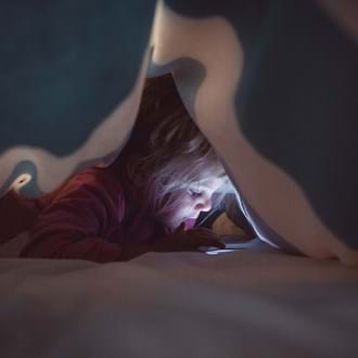 Girl reading on a phone under a blanket 
