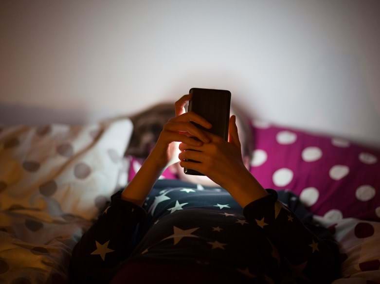Child on a bed looking at a phone